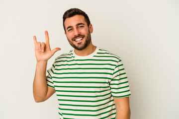 Young caucasian man isolated on white background showing a horns gesture as a revolution concept.