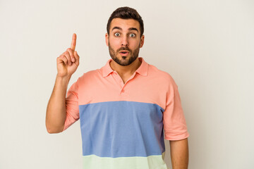 Young caucasian man isolated on white background pointing upside with opened mouth.