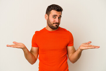 Young caucasian man isolated on white background doubting and shrugging shoulders in questioning...