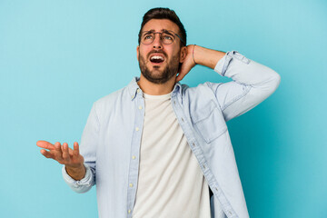 Young caucasian man isolated on blue background screaming with rage.