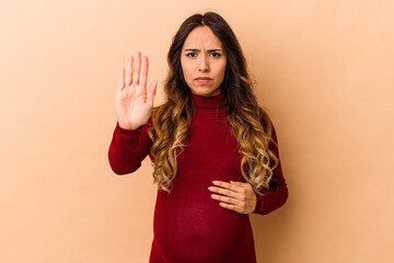 Young mexican pregnant woman isolated on beige background standing with outstretched hand showing...