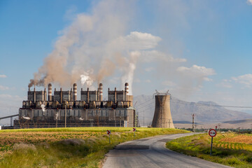 Steaming cooling towers on green meadow