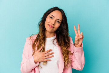 Young mexican woman isolated on blue background taking an oath, putting hand on chest.