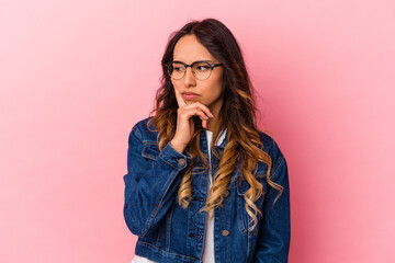 Young mexican woman isolated on pink background contemplating, planning a strategy, thinking about the way of a business.