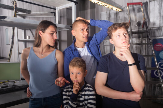 Two Interested Teen Boys With Their Parents Trying To Get Out Of Closed Space Of Escape Room Stylized Under Abandoned Nuclear Bunker, Contemplating Solving Conundrums..