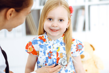 Happy smiling female kid-patient at usual medical inspection. Doctor and young girl in the clinic. Medicine, healthcare concepts