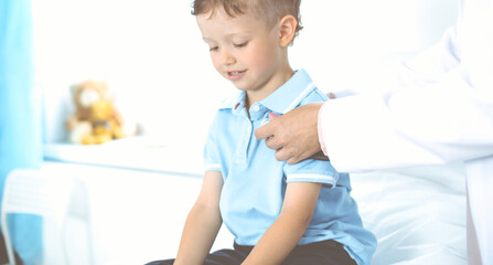 Happy smiling male kid-patient at usual medical inspection. Doctor and young boy in the clinic. Medicine concepts