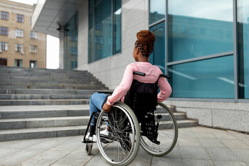 Fototapeta na wymiar Young black impaired lady in wheelchair cannot go up stairs without ramp, feeling limited and unhappy, copy space