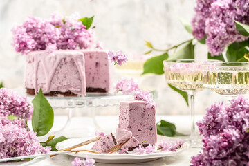 Obraz na płótnie Canvas Delicious dessert blueberry tart with fresh berries, sweet tasty mousse cake, berry pie. French cuisine, with a bouquet of purple blooming lilacs