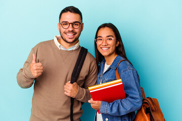 Young mixed race student couple isolated on blue background smiling and raising thumb up