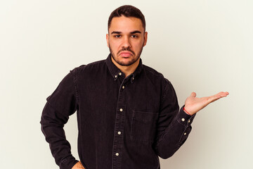 Young caucasian man isolated on white background doubting and shrugging shoulders in questioning...