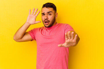 Young caucasian man isolated on yellow background being shocked due to an imminent danger