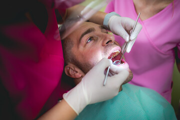 A doctor,dentist,examines the teeth of a younger man in a dental office.