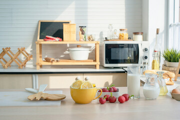 Modern kitchen with a cup of milk, wooden fork and spoon on table, sun light from window