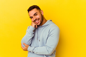 Young caucasian man isolated on yellow background smiling happy and confident, touching chin with hand.