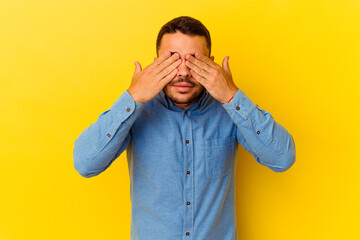 Young caucasian man isolated on yellow background afraid covering eyes with hands.