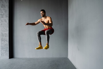 Young fit muscular shirtless sportsman jumping exercising