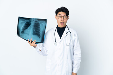 Young Chinese doctor man holding radiography isolated on white background with surprise facial...