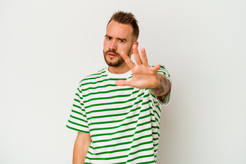 Young tattooed caucasian man isolated on white background being shocked due to an imminent danger
