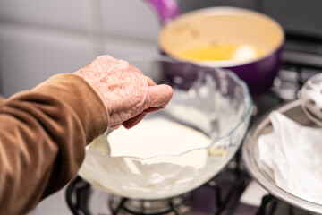 Close-up at Grandmother's hand preparing a delicious cake. Cooking time.