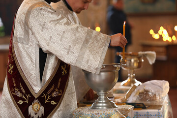 MYKOLAIV, UKRAINE - FEBRUARY 27, 2021: Deacon and priest conducting baptism ceremony in Kasperovskaya icon of Mother of God cathedral, closeup