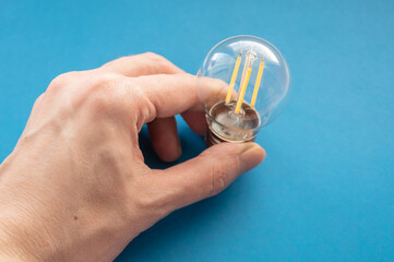 Hand holding led lamp on the blue background. Selective focus.