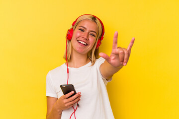 Young venezuelan woman listening music isolated on yellow background