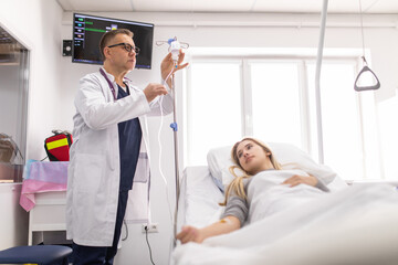 Doctor working, checking Intravenous drip, I.V. tube saline fluid bag for cure patient in hospital room. Handsome professional doctor care his patient by checking I.V. tube saline bag by himself