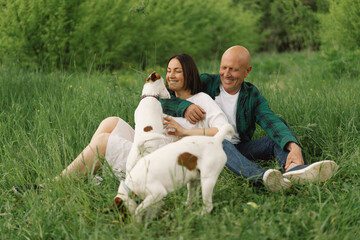 Family play Jack Russell Terrier dog in meadow. Family hugging Jack Russell Terrier dog in nature. Beautiful dog.