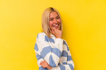 Young venezuelan woman isolated on yellow background smiling happy and confident, touching chin with hand.