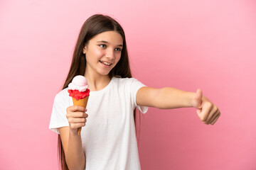 Little girl with a cornet ice cream over isolated pink background giving a thumbs up gesture