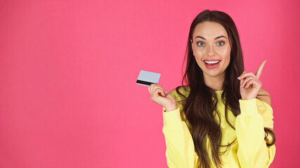 Naklejka premium excited young adult woman holding credit with idea gesture isolated on pink