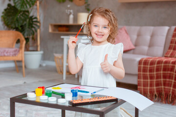 a little cute girl paints with paints at home