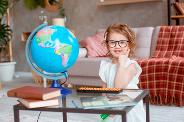 little schoolgirl girl with glasses is engaged at home