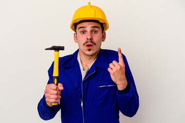 Young caucasian worker man holding a hammer isolated on white background having some great idea, concept of creativity.