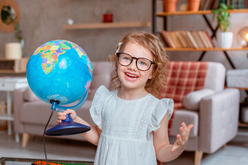 little schoolgirl girl holding a globe, Happy cute little girl doing homework, holding a globe, studying
