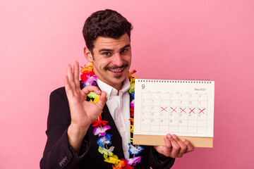 Young caucasian business man counting the days for vacations isolated on pink background cheerful...