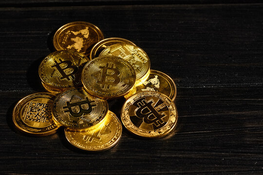 Closeup golden coin with bitcoin logo. Leader in cryptocurrency Bitcoin BTC on a top of coins against black wooden surface. Pile of decentralized digital currency. Crypto payment. Electronic money.
