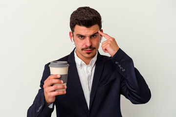 Young business caucasian man wearing wireless headphones and holding take way coffee isolated on white background pointing temple with finger, thinking, focused on a task.