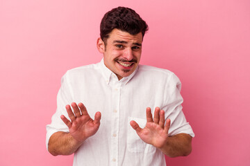 Young caucasian man isolated on pink background rejecting someone showing a gesture of disgust.