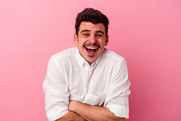 Young caucasian man isolated on pink background laughing and having fun.