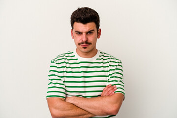 Young caucasian man isolated on white background frowning face in displeasure, keeps arms folded.