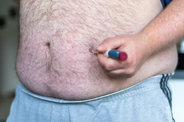 close up of fat man hands making injection with insulin pen or syringe, medicine, diabetes, glycemia, health care and people concept.