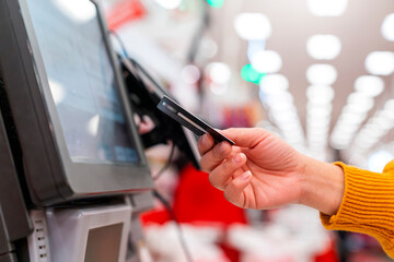 close up human female hand 
 with pos cashier machine Retail, credit card payment service. Customer paying for order of cheese in grocery supermarket store shop. - obrazy, fototapety, plakaty