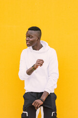 Young african American black man dancing against a yellow wall wearing a white sweatshirt. Happy and joy. Attitude