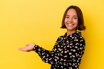 Young mixed race woman isolated on yellow background holding a copy space on a palm.