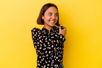 Young mixed race woman isolated on yellow background hugs, smiling carefree and happy.