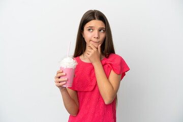 Little girl with strawberry milkshake over isolated white background having doubts and thinking