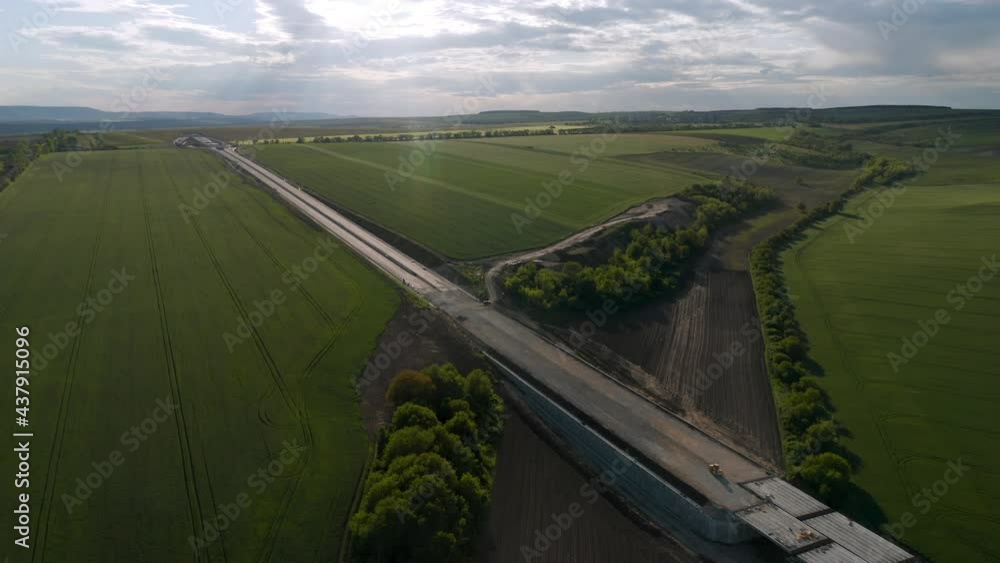 Wall mural drone flight over beautiful nature with green rolling fields and a newly built highway that passes t
