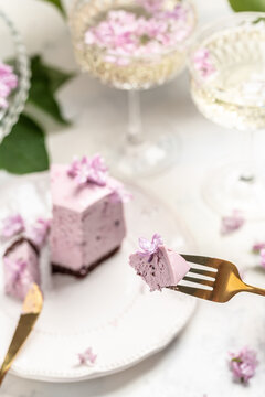 a piece of mousse cake, Delicious dessert blueberry tart with fresh berries with a bouquet of purple blooming lilacs, vertical image place for text